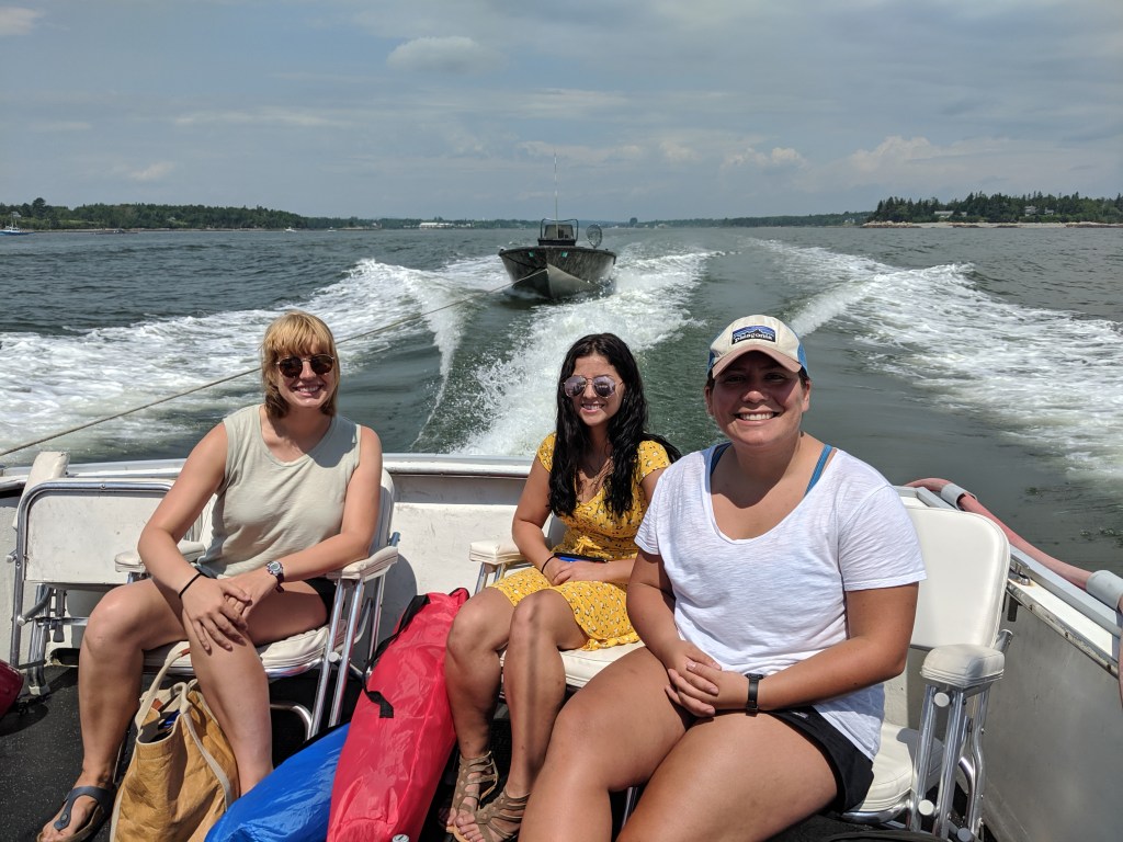 Three women sitting on a boat smiling in the sun 